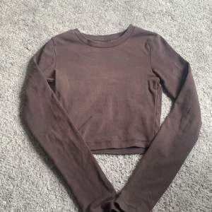 En brun tröja från Gina. Säljer pga att den inte kommer till användning. Det är en kort tröja så den går till naveln ungefär, lite ovanför💗skriv för fler bilder!❤️‍🔥
