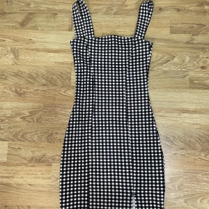 Svart och vit rutig klänning - En svart och vit, tajt klänning som har en liten slits