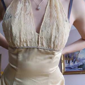 Söker du en unik Y2K klänning till balen? Säljer nu syrrans balklänning från tidigt 2000-tal. Använd 1 gång & i perfekt skick. Halterneck i spets. Knälång, jättefin färg och smyckad under bysten. Kunde ej stänga zippern (för liten) så jag fick hålla den