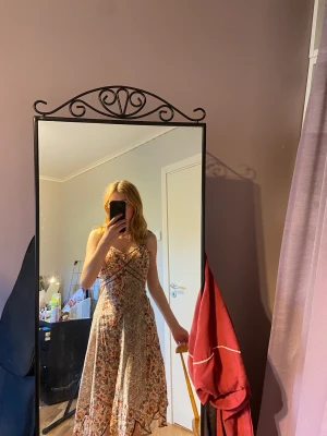 Mönstrad lång klänning - En mönstrad medellång klänning. Färgerna är åt det brunröda hållet. Den är väldigt sval och skön och perfekt för sommaren. Jag säljer den för att den är för stor. Den är knappt använd.