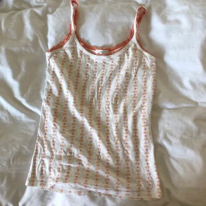 Gullig sommartopp med spets strl M - I gott skick, som oanvänd, från gammal Cubus (kanske 15 år sedan). Orange blommigt mönster med orange spets. Dm:a gärna vid frågor eller funderingar:) Köparen står för frakt. 