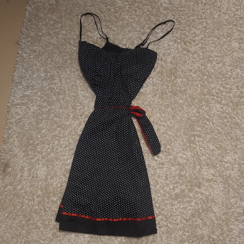 En svart klänning med vita prickar och röda detaljer, kommer inte till användning. Har bara använt 2 gånger. Snygg till sommaren🩶. Klänningar.