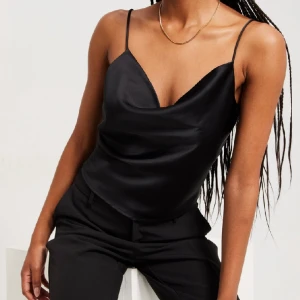 Topp - Svart topp i satin ifrån Nelly, superfin men säljer pga kommer ej till användning! Storlek M och passar på mig som är 174. Skriv för bilder eller mer info! 