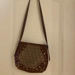 DKNY Väska - Denna har var älskad! Lite färgbortfall på en av nitarna. Axelremmen har slitage på flera ställen se extrabilder!❤️