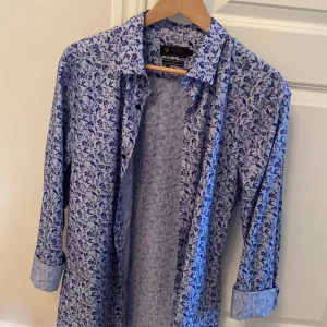 Blå sommar skjorta från Riley - Fin och tunn sommar skjorta från Riley, skjortan är i storlek L men passar även dig som vanligtvis har medium eftersom den är slim fit. Nypris är 600kr