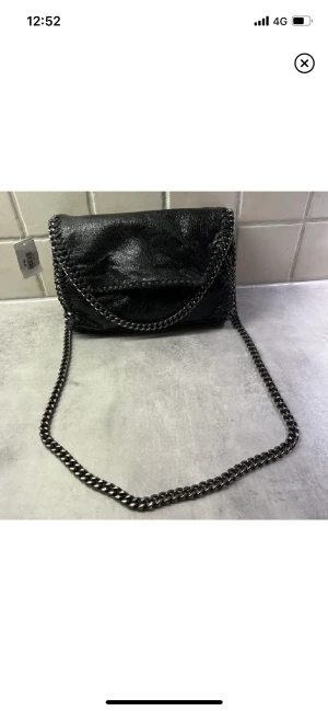 Svart handväska  - Svart väska med struktur, svarta kedjor. Oanvänd dvs nyskick. Rymligt fack med småförvaring innuti. Priset är exklusive frakt.
