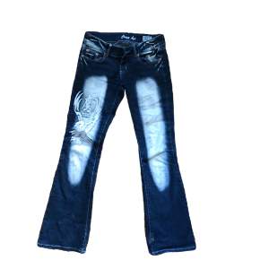 Supersnygga lowrise jeans med broderi. Saknar knapp över gylfen men det går att sy fast eller ha på sig skärp istället. Lite slitna nere vid hälen (se 3dje bild). 