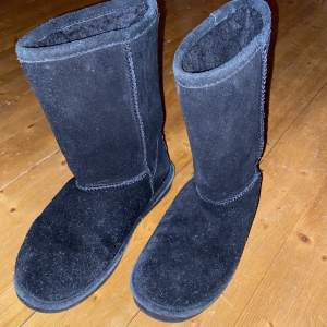 Höga svarta Uggs liknande vinterskor. Skorna är från märket Red arctic i storleken 39. Skorna är använda på vintern i blött väder och därav har materialet blivit lite nopprigt.