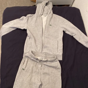 Lacoste tracksuit - Väldigt bekväm och snygg Lacoste mjukis dress. Mycket bra skick på både koftan och byxorna. Går att köpa separat, kofta(279kr) byxor(269kr) men hela tracksuiten säljs för 499kr Nypris: byxor:999kr Kofta:1099kr