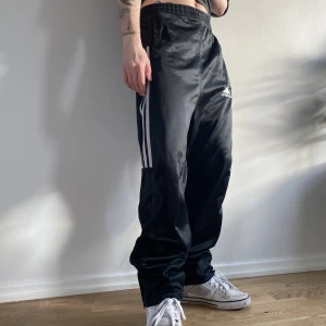 Vintage Adidas Byxor Loosefit - Snygga loosefit Adidas polyester byxor, vintage och köpte från Storbritannien. I fint skick, blixtlås vid benen, i gott skick. Passar för en person som är 175-185 cm lång. Ifall högmidjat passar dem för 165-175 cm. För fler bilder eller mått kontakta mig💫