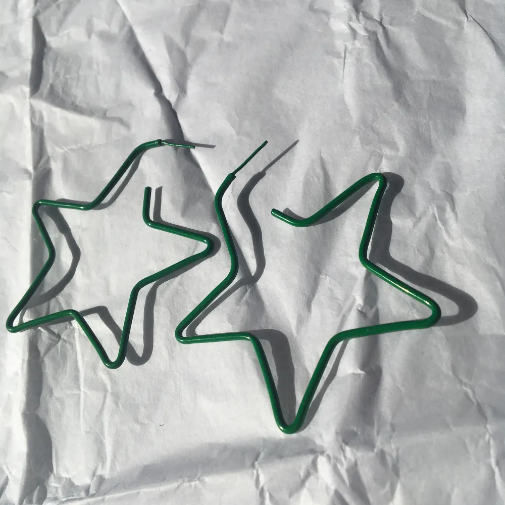 Gröna stjärnformade örhängen i okänd metall. Bra skick, dock är piggen något sned på ena. . Övrigt.