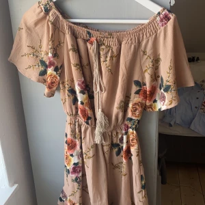 Beige/rosa jumpsuit - Jumpsuiten är beige/rosa med blommor på. Den är aldrig använd och i mycket bra skick. 