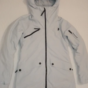 Skidjacka Peak Performance ⛷️❄️ - Helt ny Peak Performance skidjacka. I en snögrå färg och ett väldigt mjukt och lätt material💥 Modellen är väldigt feminin och justerbar i midjan 🤍😍 Storlek Xs 😊Fråga gärna efter fler bilde!!!