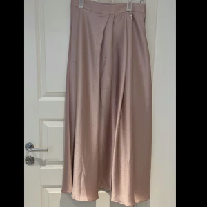 Lång kjol - satin - Jättefin kjol i satin material. Knappt använd! Den har en mjuk & fin rosa färg. Priset kan diskuteras. Fler bilder skickas om det önskas.