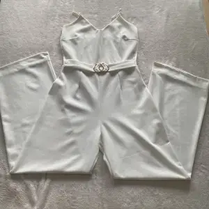En vit jumpsuit med gulddetalj. Den är endast använd en gång. Passar bra för skolavslutningar eller andra evenemang. Den har justerbara axelband och är i storlek M.