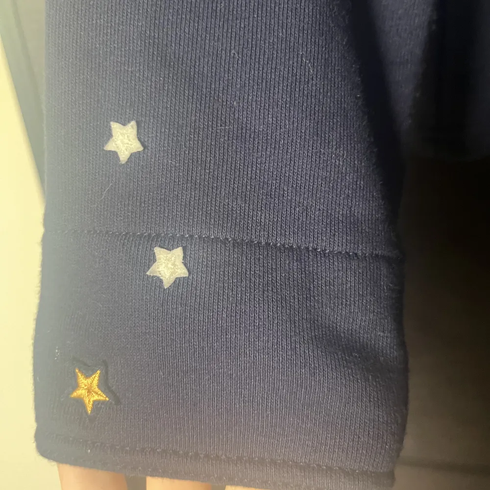 Mörkblå hoodie från Ralph Lauren köpt på kidsbrandstore. Dragkedja och ficka på framsidan, tre söta stjärnor på ena armen och broderad text på ryggen.. Hoodies.