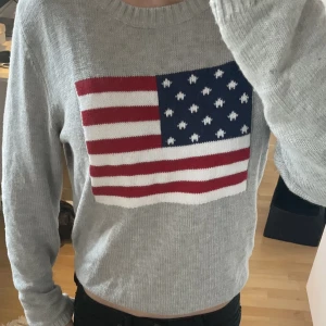 Stickad tröja me flagga  - Jättesöt grå stickad tröja med en flagga på! Använd typ en gång så fint skick! Köpt på second hand men ser typ oanvänd ut, inga defekter! Hör av er vid frågor elr intresse!💞