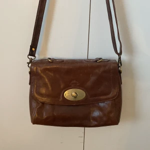 Vintage axelremsväska  - En brun väska men gulddetaljer använd en gång den är vintage💕