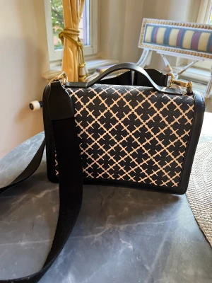 By Malene Birger väska - Loenna väska, använd en gång,  Mönstrad axelremsväska från By Malene Birger Enkelt handtag upptill Avtagbar samt justerbar axelrem Försluts med lock samt magnetknapp Ett ytterfack baktill som försluts med dragkedja Bredd: 24 cm. Höjd: 17 cm. Djup: 8,5 cm.