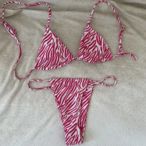 Rosa mönstrad bikini   - En rosa mönstrad bikini som aldrig kommit till användning (endast provad). Stringbikini som sitter super snyggt bak samt att den inte knyts  upp i nacken. 