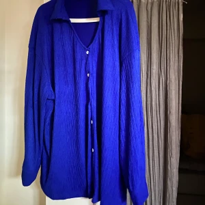 Kornblå plisserad skjorta med vita knappar  - Aldrig använd. 