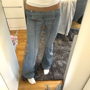 Lågmidjade jeans - Lågmidjade jeans med bälte i midjan. Längden är bra på mig som är 172. Tyvärr är själva spännet till bältet borta men man kan spänna fast bältet med säkerhetsnålar som man ser på bild 1 & 3. De har några pyttesmå fläckar men inget man tänker på. 