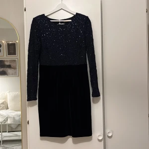 Klänning från Nelly Eve Strl 38 - Blå klänning från Nelly Eve i Strl 38. Klänningen har paljetter upptill, sammetsmaterial nedtill och har öppen rygg. Jag är 168 cm för längdreferens.