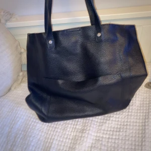 Svart väska - Bra väska som får plats med böcker och dator! Fack endast på utsidan. Tillkommer ett axelband. Liten skada på banden.