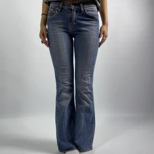 Lågmidjade jeans med nitdesign - 15. "Lågmidjade jeans med nitdesign"  Midja tvärs över: 34 cm Innerbenslängd: 74 cm  Modellen är 172 cm lång och bär vanligtvis storlek 34/36