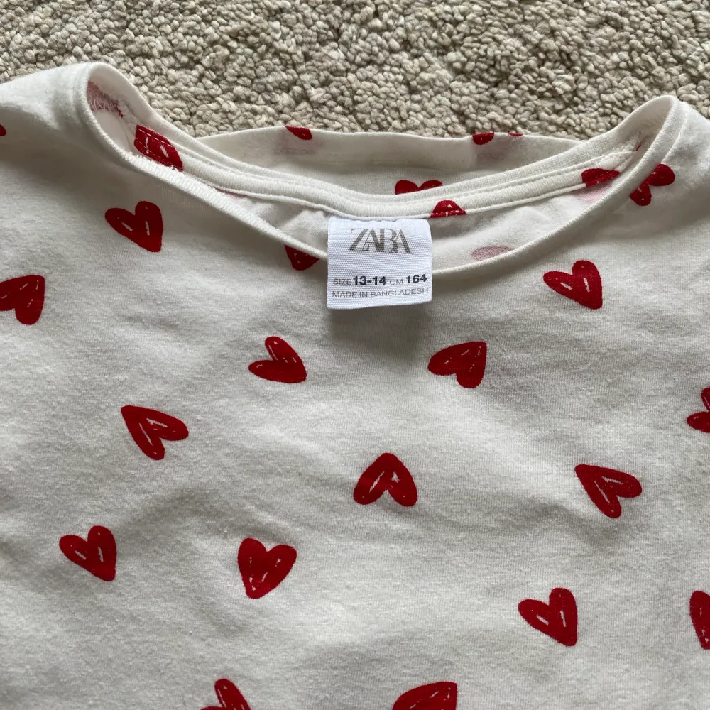 Säljer en vit -shirt med hjärtan på från zara. T-shirten har andvänds ett få antal gånger och är i bra skick. Storleken är 164. T-shirts.