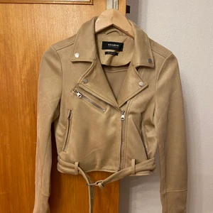 Bikerjacka i mockaimitation beige - Beige Bikerjacka i mockaimitation i storlek s från pull and bear, fint skick då den endast är använd 1 gång! Kan hämtas i Malmö men även fraktas, köparen står för frakten!😊