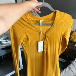  - En helt ny gul tröja från Nelly. Är i storlek S, knappar som går att stänga och öppna. 