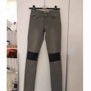  - Gråa jeans med PU/läderdetaljer. Aldrig använda. Låg midja.