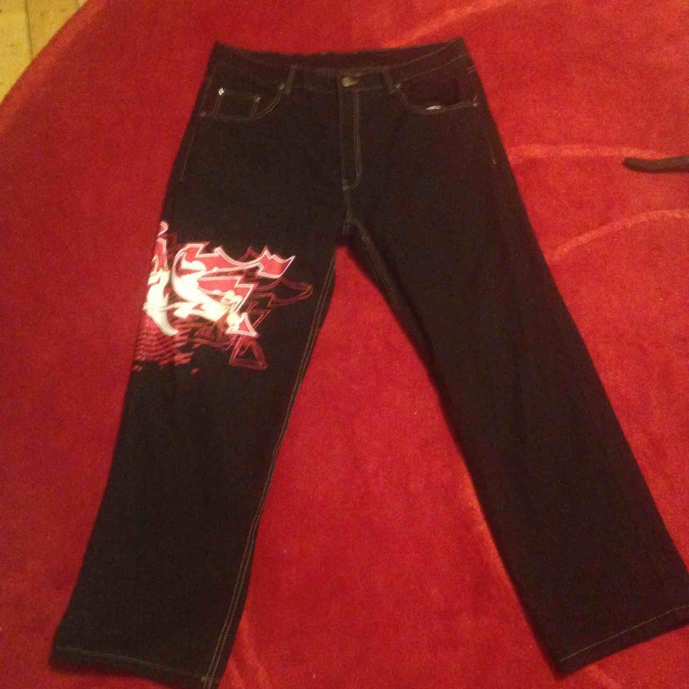 Jätte coola townz jeans som är svarta med röd/vit grafittin målning runt vänstra benet. . Jeans & Byxor.