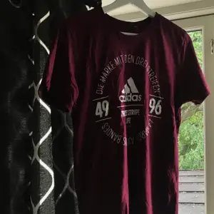 Sparsamt använd Vinröd Adidas T-shirt med tryck på framsidan nypris 249 kr säljes pågrund av används inte. Köparen står för frakt 