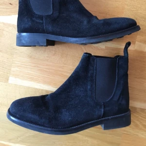  - Svarta chelsea-boots i mocka från Rizzo. Något fyrkantig tå i stil med R.M Williams. Greppvänlig sula som funkar bra på halt underlag. Kommer se ut som nya om man använder lite svart mockafärg. 