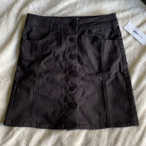 Svart jeanskjol från Gina Tricot  - Säljer en helt ny svart jeanskjol med knappar från Gina Tricot i storlek 34. Köparen står för eventuell frakt på 60kr 