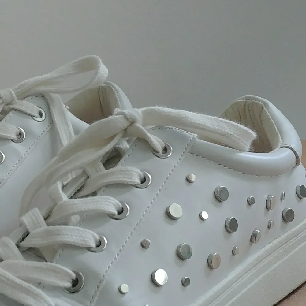 Vita sneakers i skinnimitation med coola nit-detaljer på sidorna. Endast använda fåtal gånger och därav mycket bra skick. Skor.