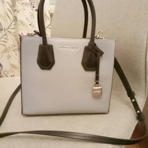 Michael Kors Mercer handbag collection - Elegant samt casual handbag.Den är i fin skick då den är knappt använt. Färg: Baby blue, vitt och mörk blå med silver signatur lock charm. Ord. pris: 2 300.00kr (men verkar som den inte finns kvar på deras webbsida något mer. Om mer info önskas kan ni söka på MK's webbsida (för liknande i andra färg): "MICHAEL Michael kors Mercer color-block leather crossbody bag".  Endast hämtning på Tulegatan (Sundbyberg) eller frakt (men då står mottagaren för frakt kostnad). 