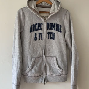 Abercrombie and fitch hoddie i grå  - En grå hoodie från Abercrombie and fitch. Jätte skön och fin hoodie till kjol och byxor. Passar till allt. Ett mycket bra plagg som kommer få bra användning i ditt hem. 