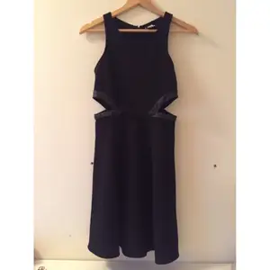Klänning med klockad kjol och ngt glansigare material (utan att det är glansigt, mer tydligt svart bara). Skinndetalj i midjan 