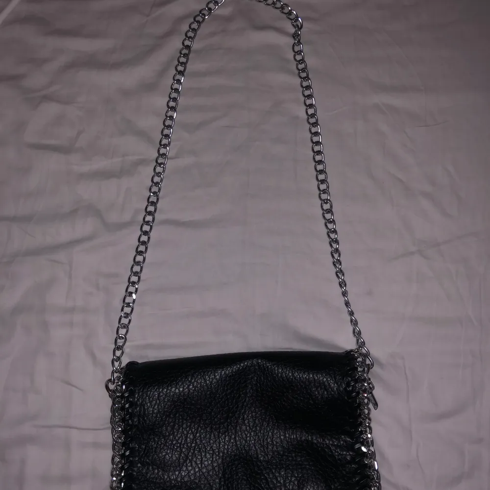 En svart väska med kedjor köpt från scorett. Silverfärgen på kedjorna har gått bort lite på sidorna av väskan annars inga hål eller liknande. Säljs då den inte kommer till användning. . Väskor.