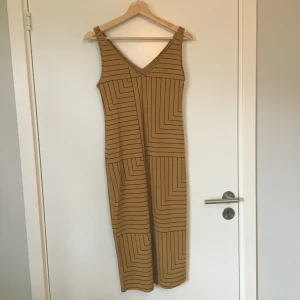 Mönstrad klänning Lindex - Vadlång mönstrad klänning i senapsgult och svart från Lindex. Gott skick. Frakt betalas av köparen.