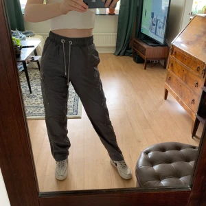 Byxor från Zara - Mörkgråa glansiga byxor från Zara. Mycket tunt och luftigt material. Stora fickor på båda benen och dragkedjor längst nere vid foten. Storlek XS men de är luftiga så passar mig som vanligtvis har S! Aldrig använda 😙