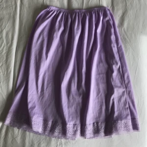 Underkjol - Syrénlila underkjol i polyester! Spetskant med en liten slits. 