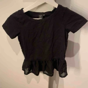  - En såå fin T-shirt med volanger ner till, är i storlek 134/140 men passar perfekt att använda som magtröja. Bra skick. Köparen står för frakten