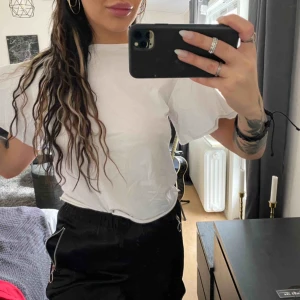  - En vit vanlig basic tisha, dock med en liten detalj som är ärmarna. Lite utsvängda. Snyggt! Strl s