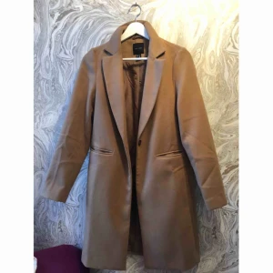  - Beige kappa från Nelly. Kappan är oanvänd och i mycket bra skick