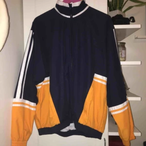  - Tunn jacka, i marinblå och orange. 