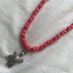 Halsband - Jättefint halsband i orange och rosa med en sköldpadda berlock i mitten🤩🐢 Stängs med en karbinhake. 45kr inkl frakt!